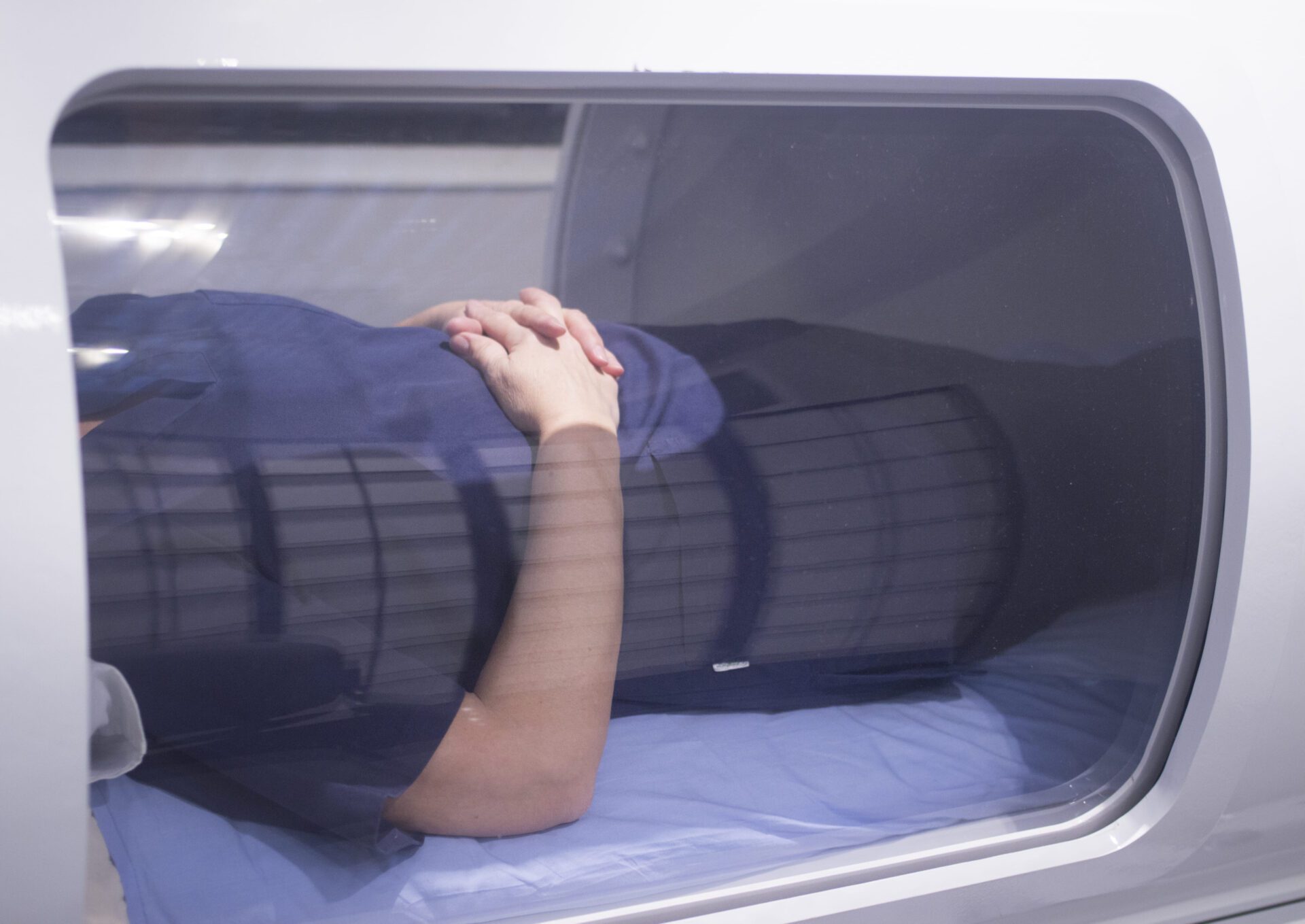 Female patient lying down in hyperbaric oxygen chamber receiving Hyperbaric Oxygen Therapy (HBOT) specialised medical treatment for gut damage.